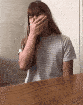 a girl covering her mouth with her hand while wearing a striped shirt