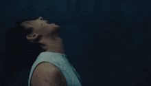 a man in a white tank top is looking up into the sky