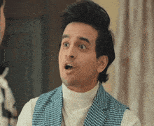a man wearing a white turtleneck and a blue and white vest is making a surprised face