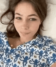 a woman is laying on a bed wearing a blue and white pajama top with monkeys on it .