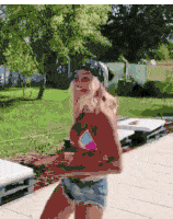 a woman in a bikini and shorts is wearing a hat and dancing .