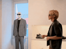 a man wearing sunglasses looks at a mannequin in a suit