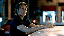 a man smoking a cigarette on the roof of a car