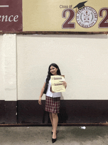 a girl stands in front of a sign that says class of 2022