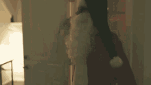 a man dressed as santa claus is standing in a hallway .