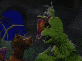 two stuffed animals are standing next to each other and one is a green monster