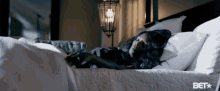 a woman is sleeping in a bed with a bet logo on the bottom