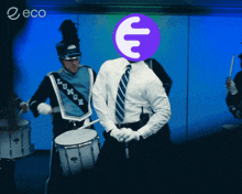 a man with a purple e on his head is playing drums