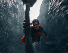 a man in a superman costume is holding a pole in the air