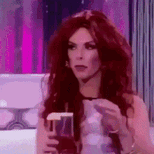 a woman with red hair is holding a glass of wine and a cigarette .
