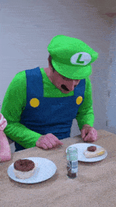 a man in a luigi costume sits at a table with two plates of food on it