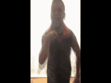 a man is standing in front of a window wearing a black vest and a red scarf around his neck .