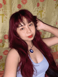 a woman with red hair is wearing a blue tank top
