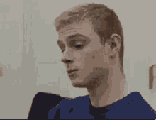 a man in a blue shirt is sitting in a chair and looking at something .