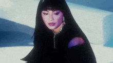 a woman with long black hair and a chain around her neck is wearing a black jacket .