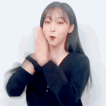 a woman in a black shirt has her hands on her face