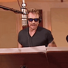 a man wearing sunglasses and headphones is talking into a microphone .