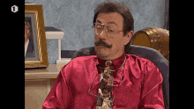 a man in a red shirt and tie is sitting in a chair