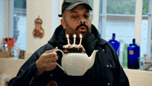 a man is blowing out candles on a cake made out of a teapot