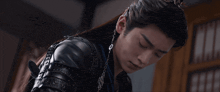 a man with long hair is wearing a black leather jacket and earrings