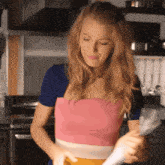 a woman in a pink top is holding a spatula