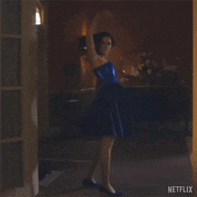 a woman in a blue dress is dancing in a hallway with a netflix logo in the corner .