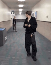 a man walking down a hallway with a trash can in the foreground