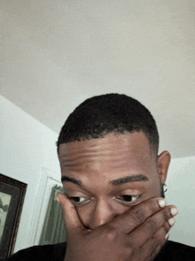 a man covering his mouth with his hand and looking at the camera