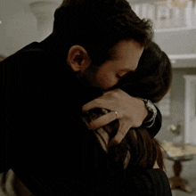 a man wearing a watch is hugging a woman with his eyes closed