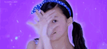 a girl wearing a blue headband is making a face with her hands