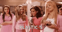 a group of girls in pink clothes are standing next to each other in a mall and talking to each other .