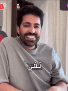 a man with a beard is smiling in a video with arabic writing on it .