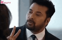 a man in a suit and tie is making a peace sign .