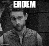 a black and white photo of a man with a beard wearing a tank top with the word erdem on it .