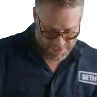 a man wearing glasses and a blue shirt with a patch that says seth