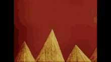 a cartoon character is standing on top of a mountain with pyramids in the background .