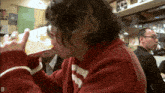 a man in a red sweater is drinking from a glass with the letter d on the bottom