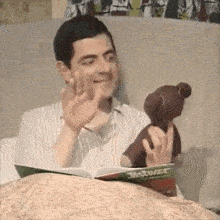a man is reading a book while holding a teddy bear