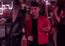 a man in a red jacket is standing next to a woman in a black dress at a party .