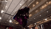 a woman in a purple dress is hanging from the ceiling in a stardom wrestling match