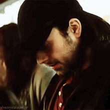 a man with a beard wearing a hat and a jacket .
