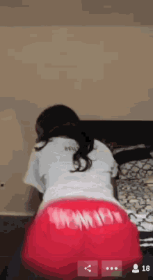a woman in a white shirt and red shorts is dancing