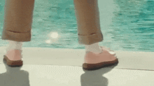 a person wearing pink shoes and white socks is standing next to a swimming pool .