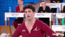 a man in a maroon shirt with the letter a on his chest