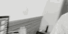 a black and white photo of a person sitting at a desk with a laptop and a cell phone .