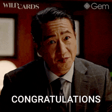 a man in a suit and tie says congratulations in front of a gem logo