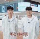 two korean men are standing next to each other in front of a korean airlines sign