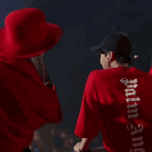 a man wearing a red shirt that says palm angels on it