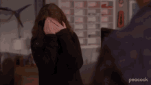 a woman is covering her face in front of a peacock ad