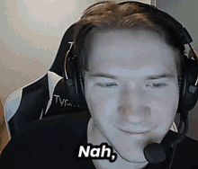 a man wearing headphones and a microphone is smiling and says nah .